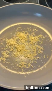 Parmesan sizzling in a light gray nonstick pan, beginning to cook with a few drops of oil visible—the perfect aromatic base for making delicious Low Carb Mortadella Wraps.