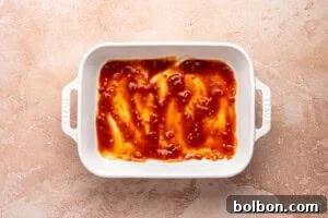 Classic Eggplant Parmesan (Parmigiana di Melanzane) Recipe 8 A white rectangular baking dish with a thin layer of sauce across the bottom.