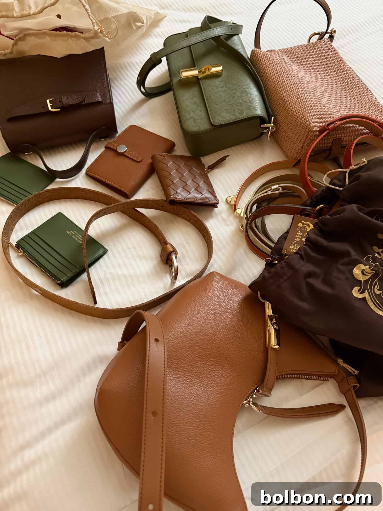 Various handbags, wallets, belts, and pouches in brown, green, and pink tones are spread out on a white surface.