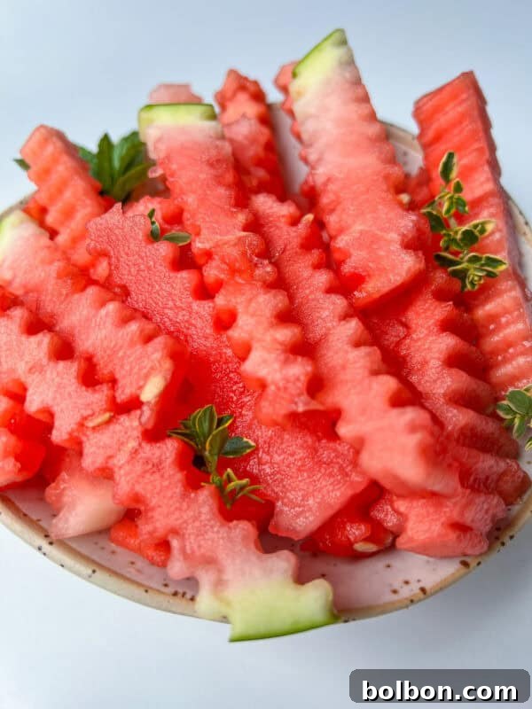 A bowl filled with crinkle-cut watermelon fries, garnished with small green herb sprigs.