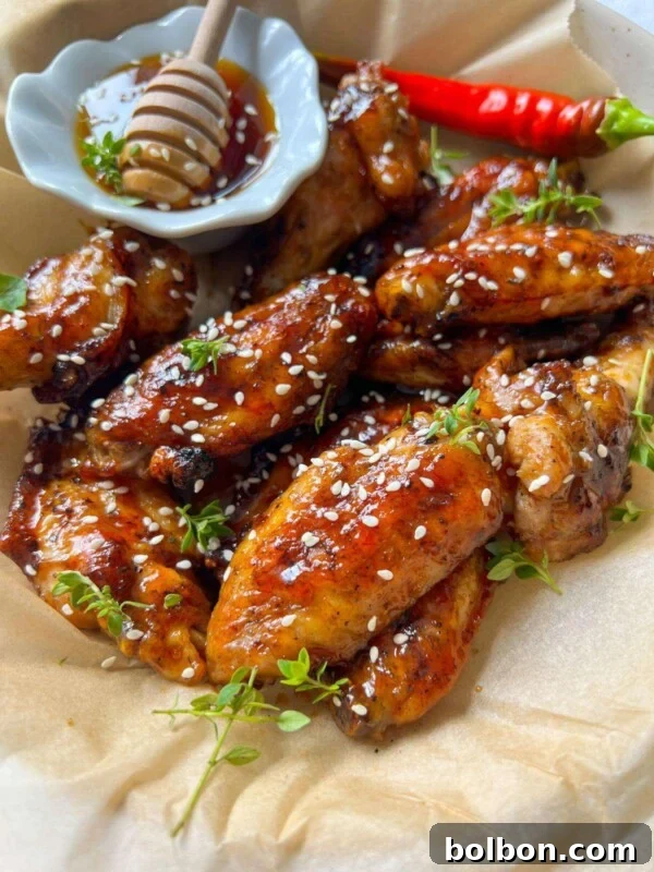 A plate of Honey BBQ Chicken Wings glazed to perfection, sprinkled with sesame seeds and fresh herbs.