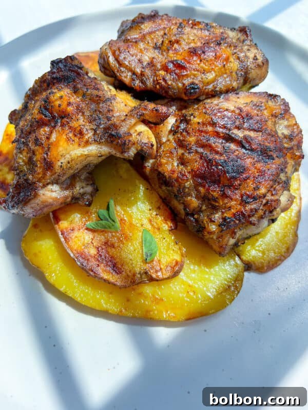 Three pieces of Grilled Chicken Thighs are served atop roasted golden potato slices.