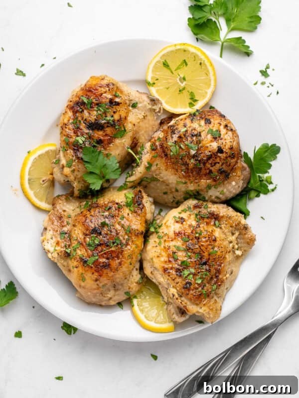 TikTok Viral Yogurt Noodles Recipe 5 A white plate with four cooked, golden-brown Lemon Yogurt Chicken thighs garnished with chopped herbs and parsley.
