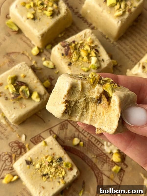 TikTok Viral Yogurt Noodles Recipe 6 A hand holds a square piece of pistachio fudge with a bite taken out of it.