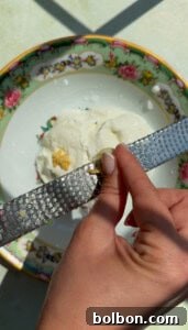 TikTok Viral Yogurt Noodles Recipe 9 A hand grates a clove of garlic over a plate with a floral rim.