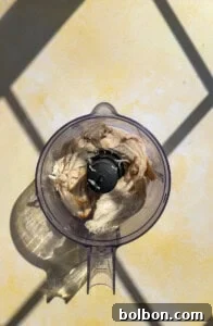 Cooked chicken pieces inside a food processor bowl