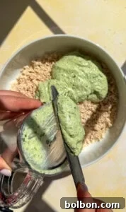 Green herb sauce being added to shredded chicken in bowl