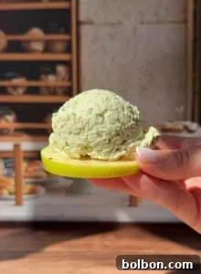 Hand holding herb cheese scoop on fresh apple slice