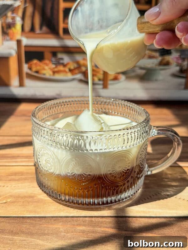 Oreo Affogato Recipe: Coffee, Ice Cream & Crushed Oreos 6 A hand pours milk into a glass mug of coffee