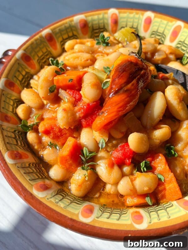 Creamy Butter Chicken Beans: Indian-Spiced Bean Curry 7 A colorful bowl filled with white beans, diced tomatoes, carrots, and herbs