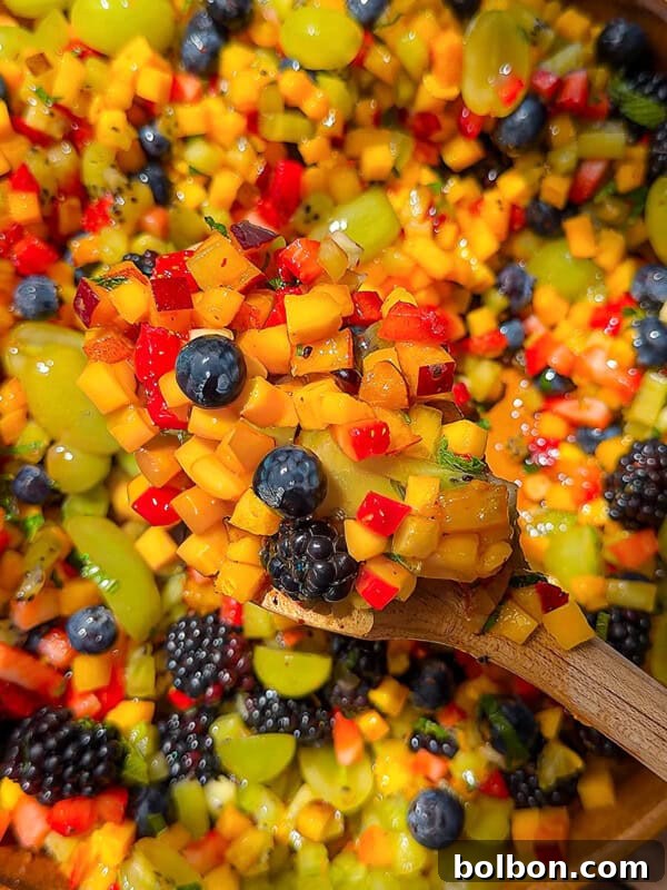 A wooden spoon holds a colorful mix of diced fruit